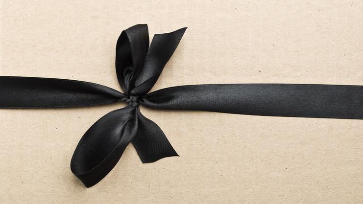 Schwarzes Satinband in Schleife auf braunem Geschenkpapier befestigt.
