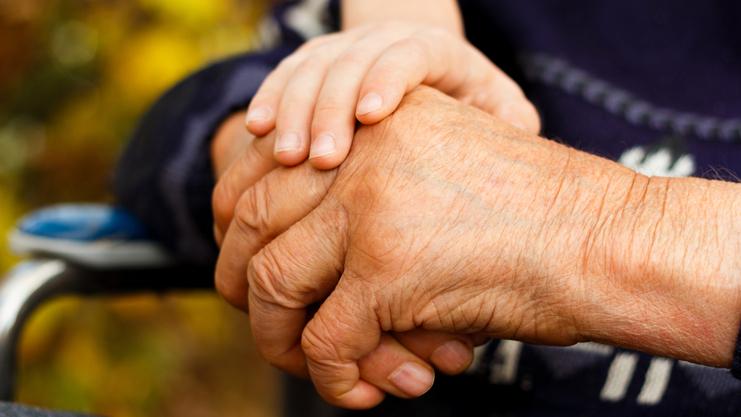 Nahaufnahme zweier Hände, eine ältere und eine jüngere, die sich miteinander halten. Hintergrund unscharf.